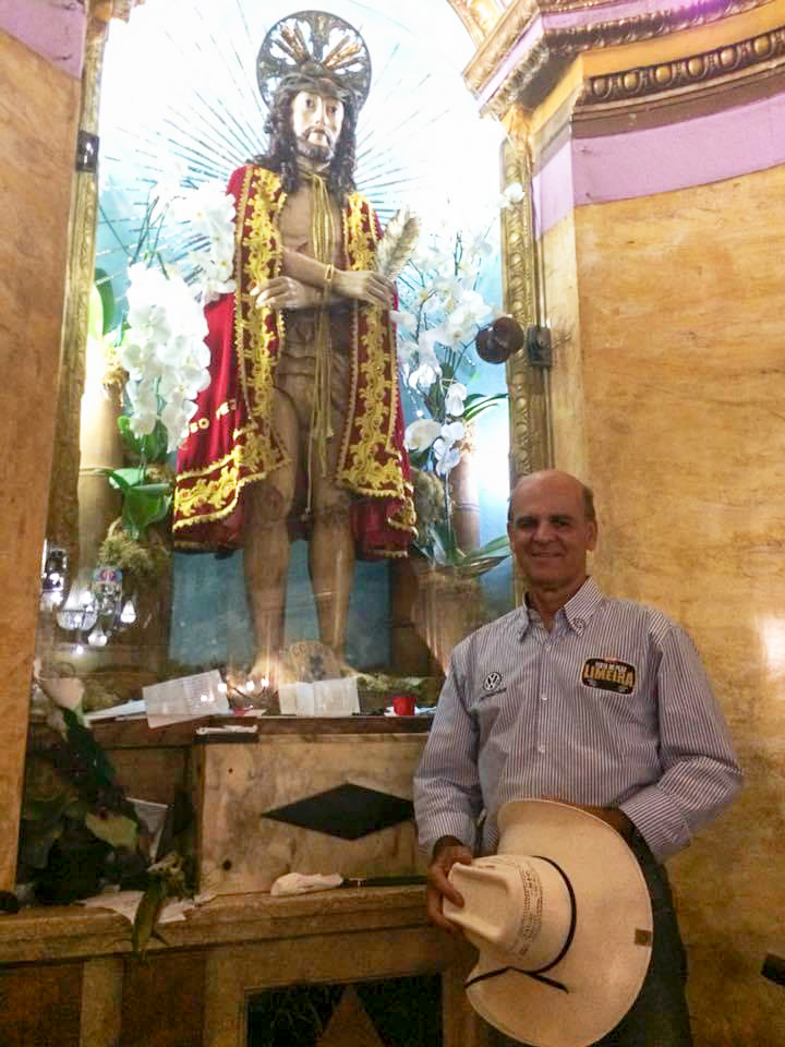 Marcelo Coghi dentro da igreja, diante da imagem do Bom Jesus de Pirapora segura seu chapéu combói 